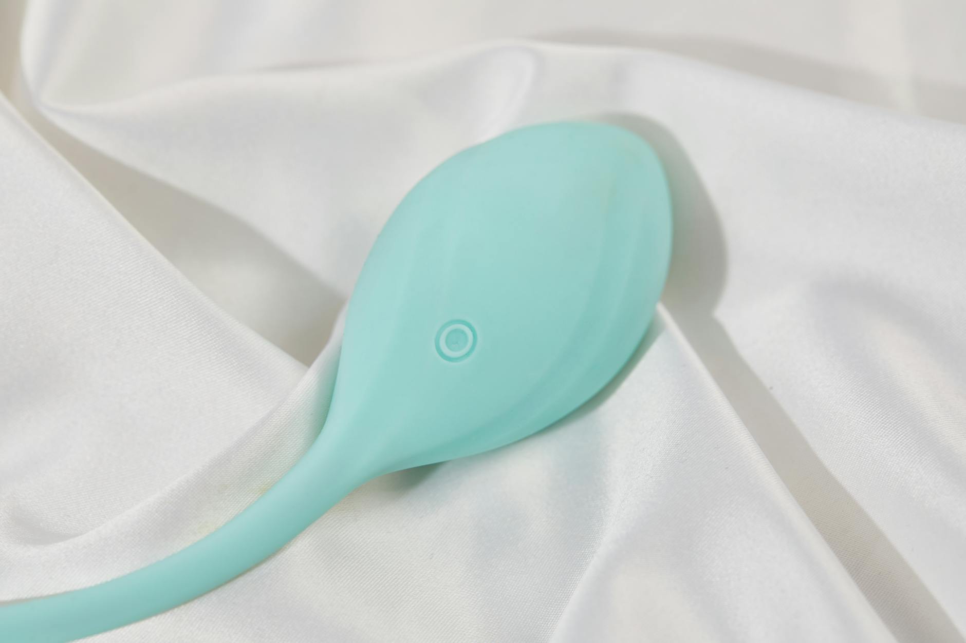 A sleek teal lemon vibrator resting on smooth white silk, representing evolving pleasure needs.