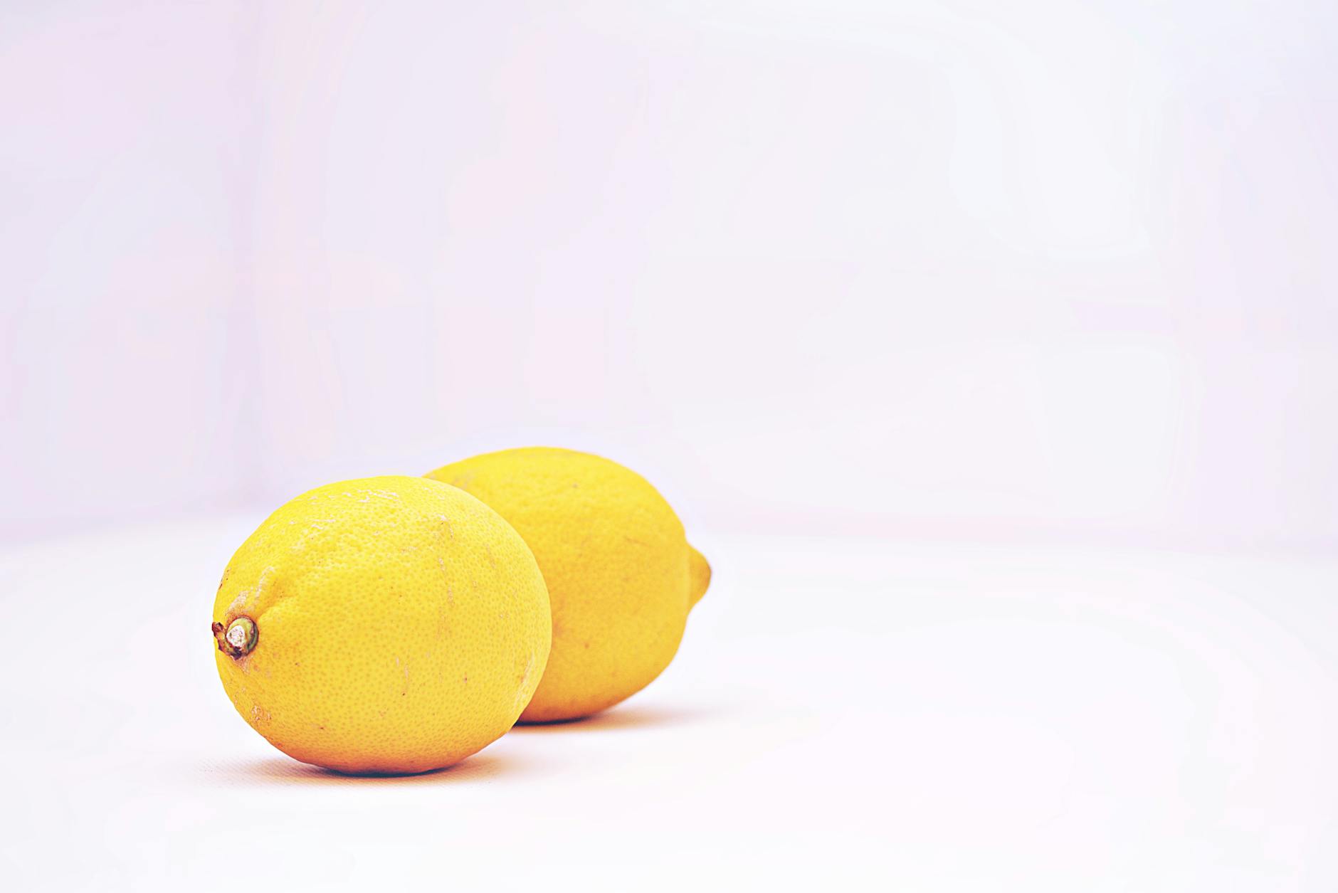Two bright lemons on a white background, symbolizing freshness and simplified sensuality