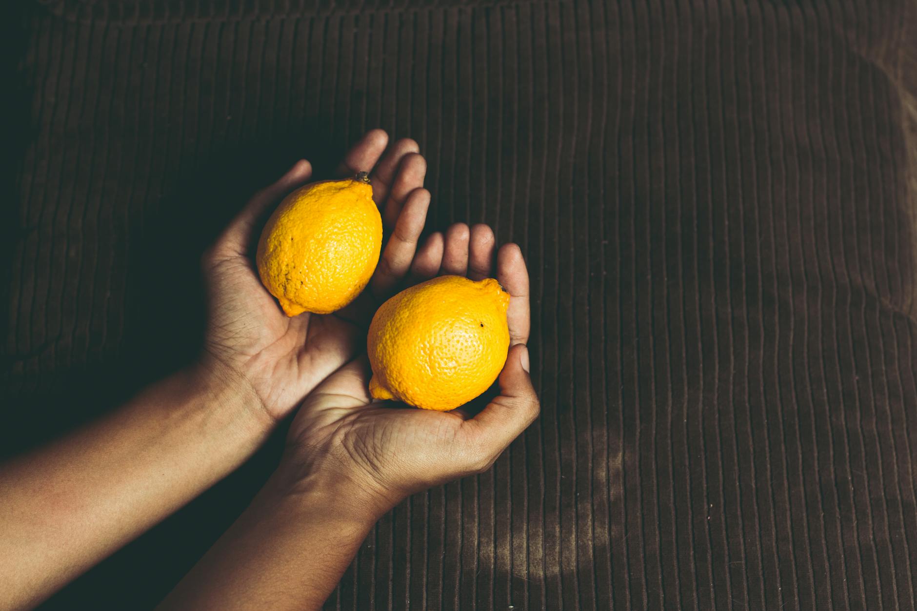Due limoni freschi tenuti in mano, simbolo di freschezza e potenziale naturale