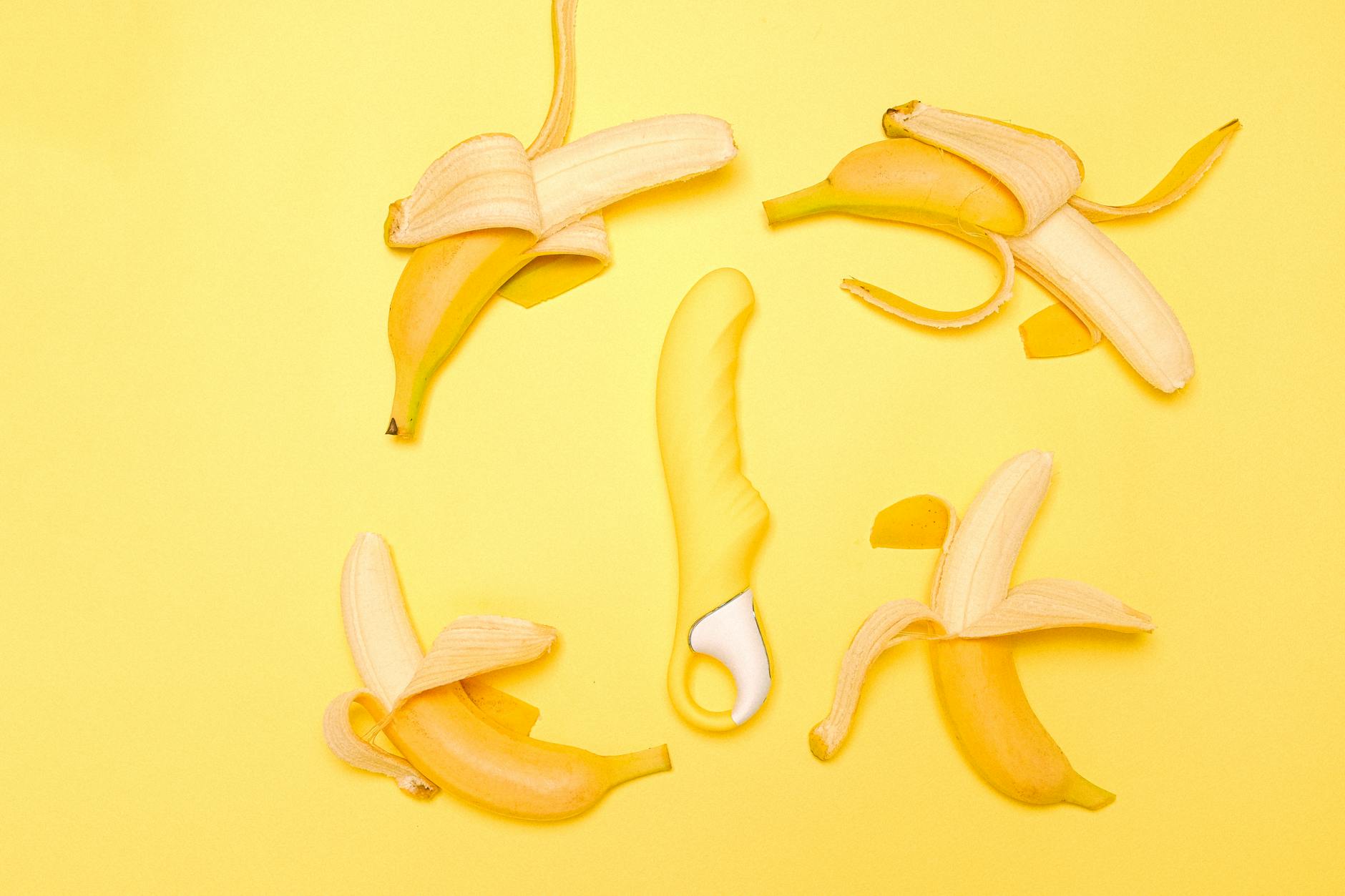 A yellow silicone lemon clitoral vibrator arranged with fresh lemons on a bright yellow background