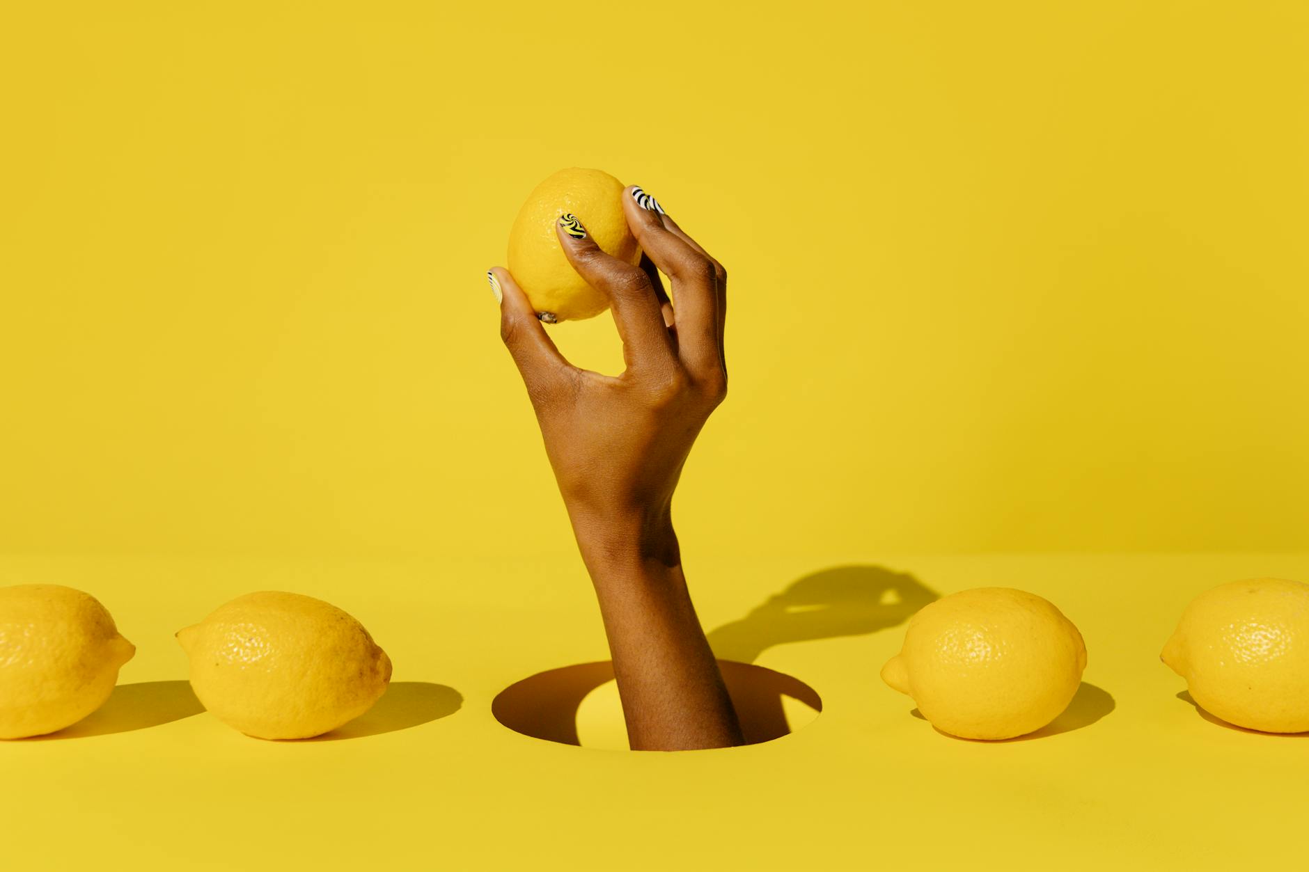 A hand holding a fresh lemon against a vivid yellow background, symbolizing renewed vitality and intensity