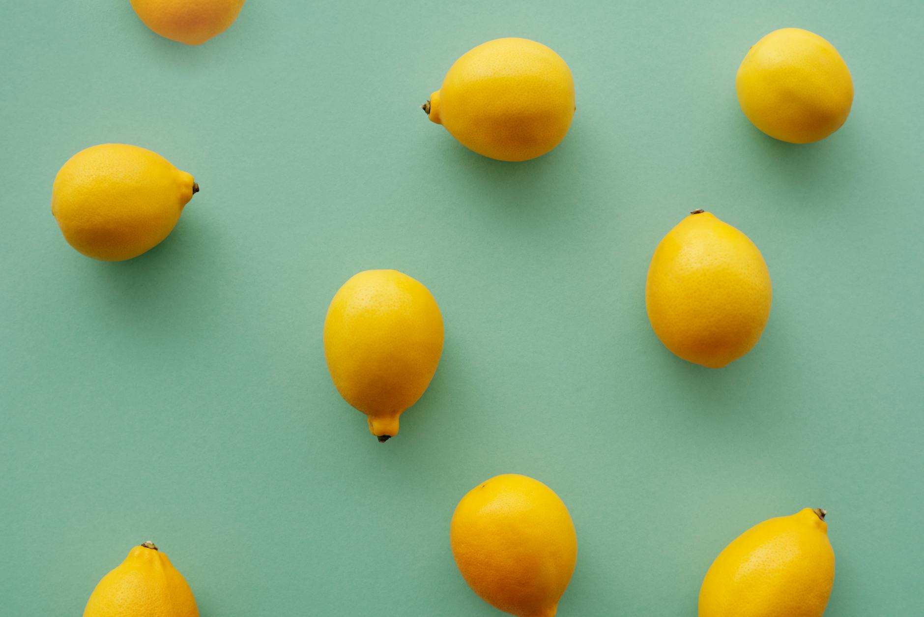 Limoni freschi e vibranti disposti su uno sfondo verde pastello, simbolo di rinascita e freschezza nel piacere di coppia