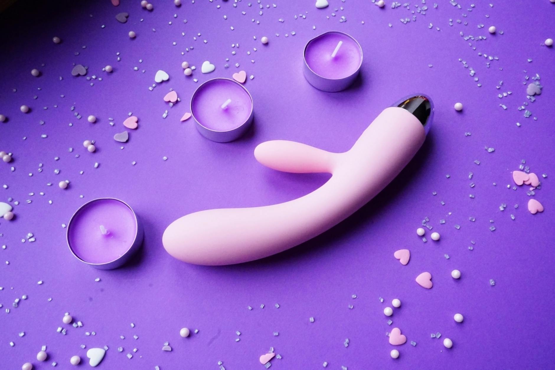 Hand holding a vibrator against a purple background, showing modern self-care practice