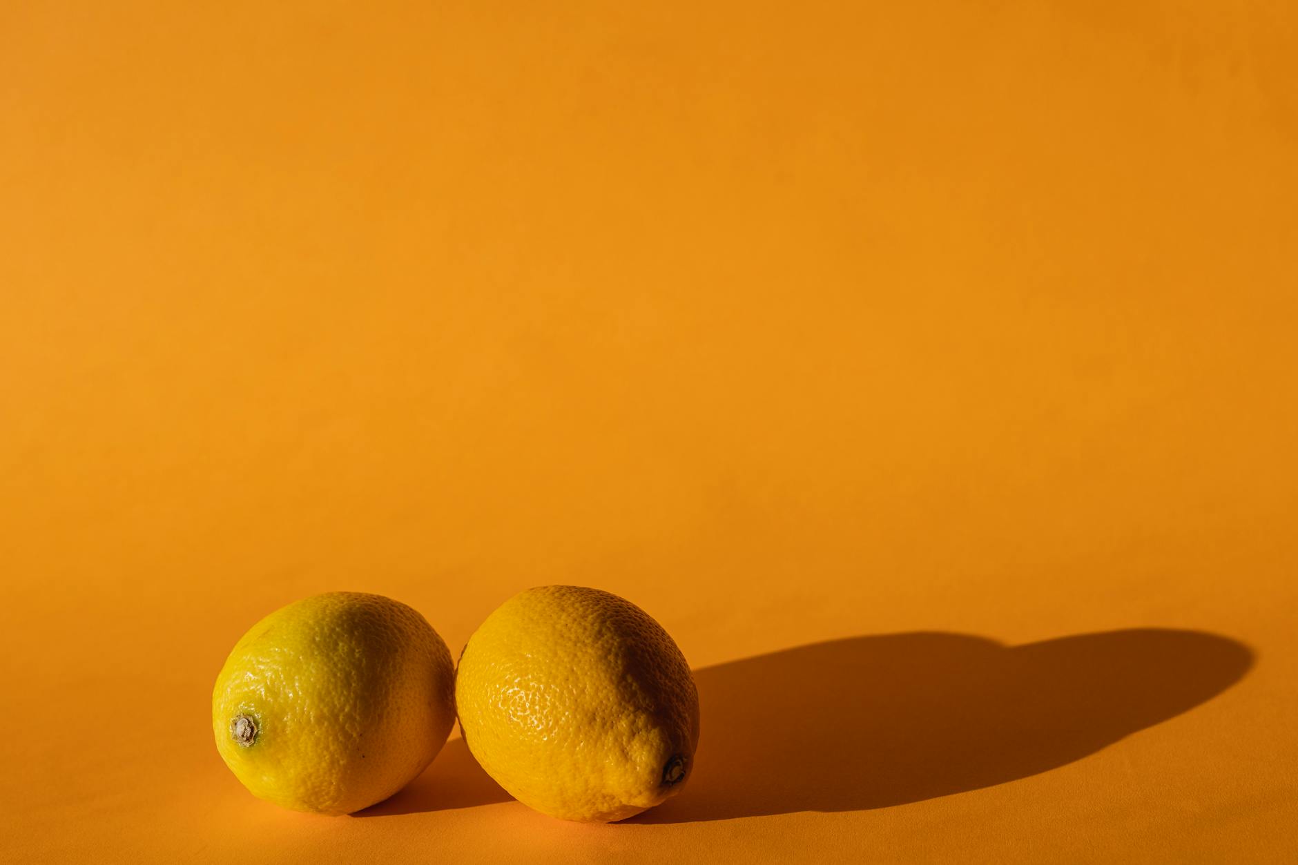 Ripe vivid lemons arranged on a yellow background, symbolizing the natural rhythm of the cycle